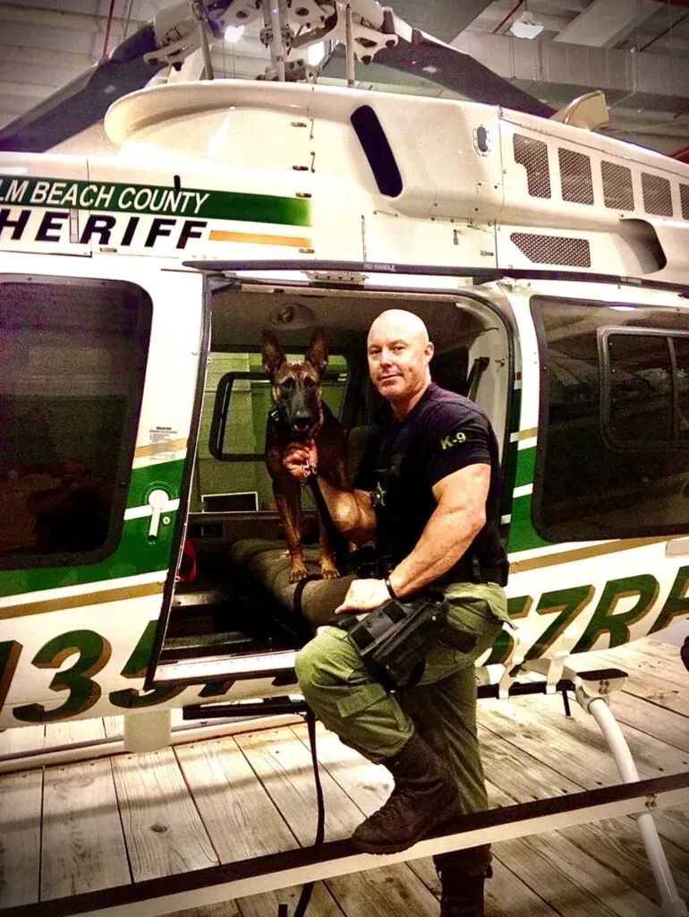 Justin Rigney, founder of K9 Services Unlimited, with a police K9 at a sheriff's helicopter