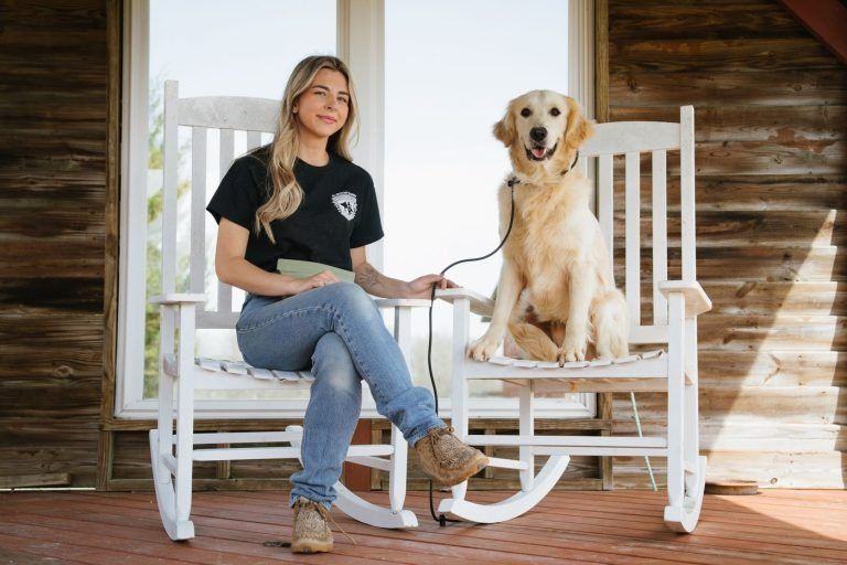 Woman and golden retriever seated on white rocking chairs on a porch